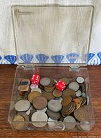 Top view of clear box showing mixed coins, two red dice and small rectangular items