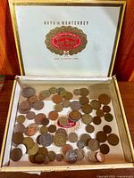 Overall view of open cigar box showing full assortment of coins