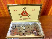 Open Montecristo cigar box showing loose commemorative quarters