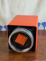 Front angled view of orange Mozsly watch winder with clear lid in place