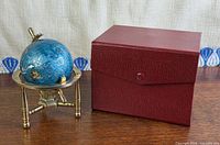 Gemstone globe on brass stand alongside original presentation box