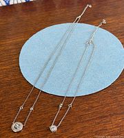 Two sterling silver pendant necklaces laid flat to show design and relative length