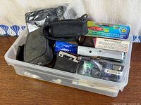 Overview of plastic bin showing multiple cameras, film, and pouches