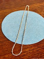 Full view of sterling silver weave necklace laid flat in oval loop