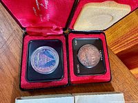 Both coins in open presentation cases, 1975 on left, 1972 on right