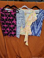 Group shot of all four women’s tops on hangers