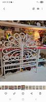 Full view of white wicker rattan twin headboard leaning against shelving