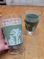 Two green footed goblets with white cameo designs, full view