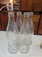 Front view of all four clear Coca-Cola bottles