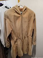 Front view of tan suede hooded parka jacket on hanger