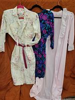 Three garments on hangers: floral shirtdress, floral knit dress, pink slip