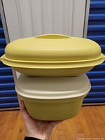Stacked view of both yellow Tupperware steamers with lids