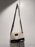 Full view of kate spade cream and black crossbody bag hanging to show overall design and strap