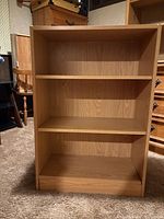 Front view showing three shelf spaces and light oak laminate finish