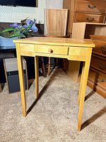 Front view of light oak solid wood accent table showing drawer and tapered legs