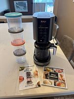 Full view of Ninja Creami machine with stacked containers, manuals visible