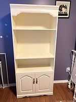 Front view of off-white MDF display cabinet with three open shelves and lower two-door cabinet closed