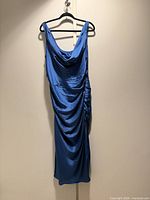 Full view of blue cowl neck dress hanging, showing overall style and side ruching
