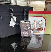 Front view showing Calvin Klein briefcase, boxed wooden sailing ship model and sealed digital photo keychain