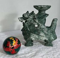 Front view of green stone dragon sculpture and cloisonné ball on white surface