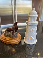 Ceramic lighthouse illuminated and stone seal figurine on wood base