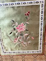 front view showing embroidered silk panel, floral motif, frame and mat