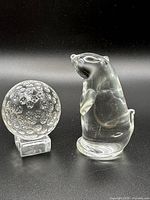 front view of glass golf ball on base and standing animal figurine