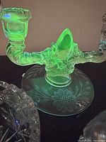 Two-light uranium glass candlestick glowing green under UV