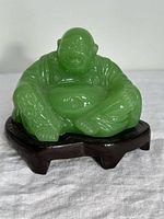 Front view of green Laughing Buddha figurine on wood stand