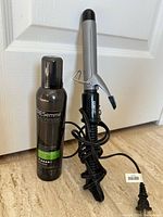 Conair curling iron coiled with cord beside sealed TRESemmé mousse can