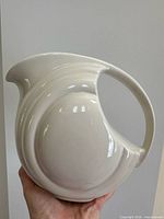 Left profile of Hall off-white ceramic pitcher showing body shape, handle and spout