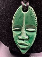 Close-up of green glazed ceramic mask pendant