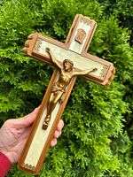 Front view of wooden crucifix with metal corpus, size reference in hand