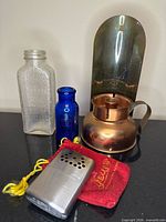 Group view of both bottles, brass sconce, hand warmer, pouch
