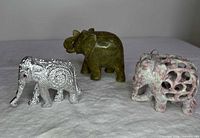 Front view of three elephant figurines showing materials and colors