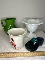 Four ceramic items: cardinal mug, milk glass compote, green pitcher, green ceramic clog
