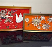 Both framed shell mosaic artworks standing side by side