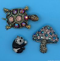 Group shot of turtle, panda and mushroom crystal brooches