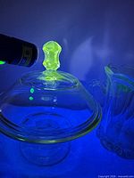 Compote lid glowing under UV beside pitcher