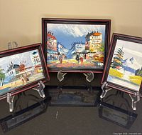 Three framed paintings on stands