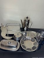 All nine stainless steel serveware pieces grouped on surface