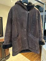 Front view of brown suede shearling hooded coat on hanger