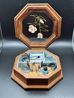 Open octagonal wooden jewelry box displaying contents