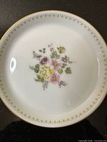 Top view of Wedgwood Mirabelle butter pat showing floral centre, green leaf border and gold rim