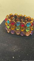 Front view of wide gold-tone stretch bracelet with multicolor stones