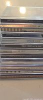 Stack of approximately 12 CD spines showing titles Cher, Justin Timberlake, Taylor Swift, Miley Cyrus, Backstreet Boys, etc.