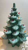 Front view of ceramic Christmas tree showing snow accents and multicolour pegs