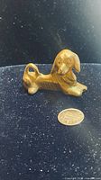 Front view of brass dachshund figurine with coin for scale