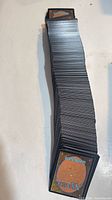 Tall vertical stack of unsleeved Magic: The Gathering cards showing card backs