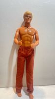 Full view of Ken doll wearing rust pants